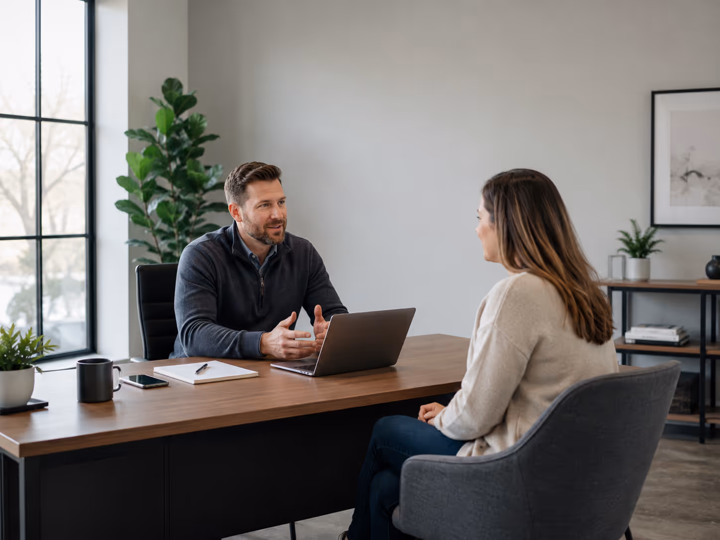 A service business professional meeting with a client in a well-lit office, reviewing plans together.