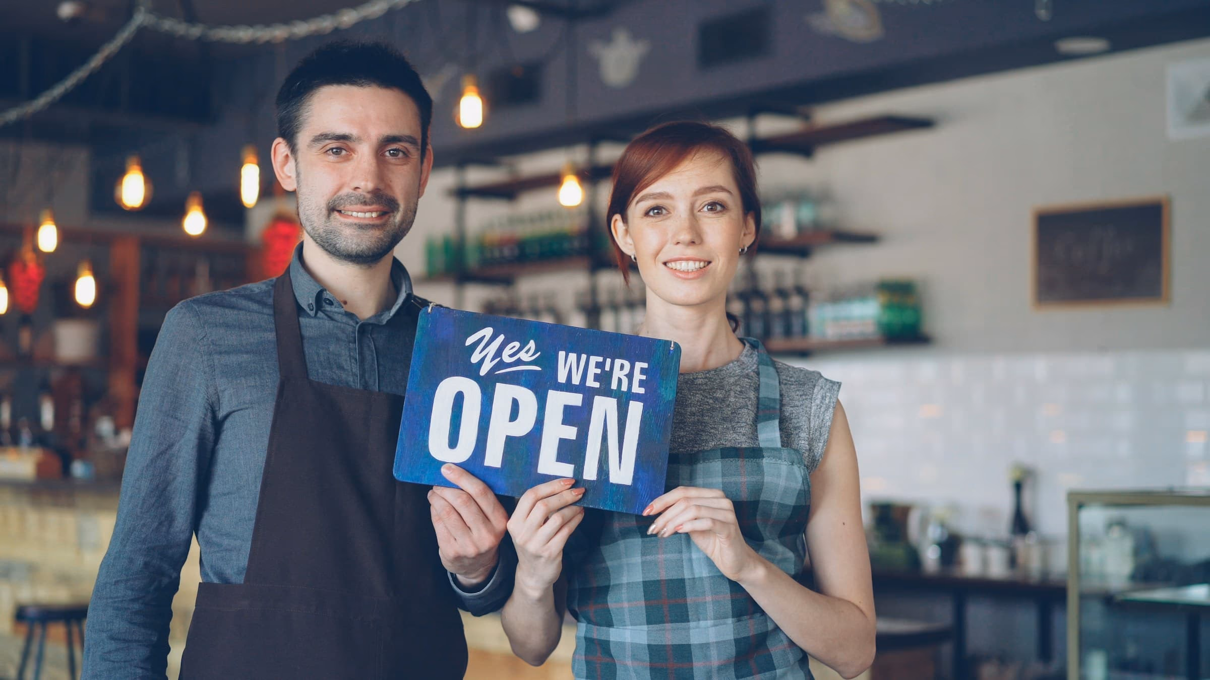 Smiling service business owners holding an open sign. Website designs for Canadian service businesses across multiple industries.