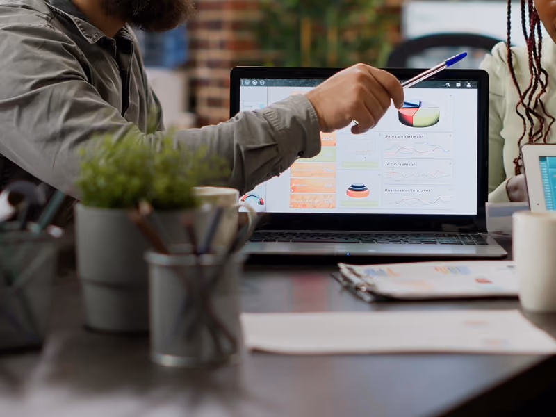 Diverse team of coworkers analyzing business charts and graphs on laptop