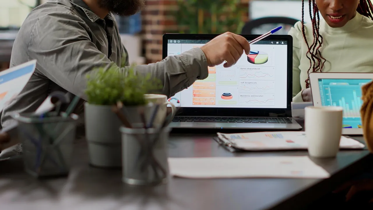 Diverse team of coworkers analyzing business charts and graphs on laptop